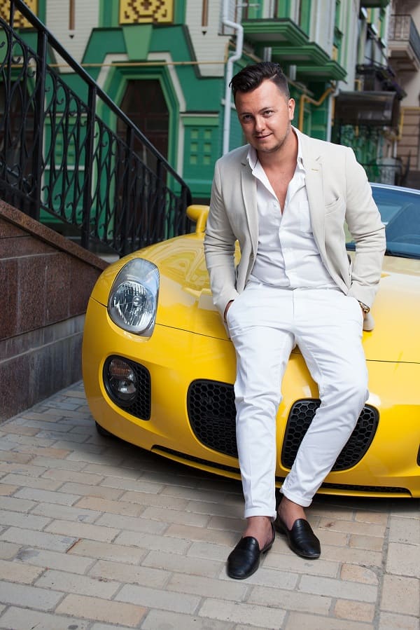 Um homem encostado na frente de um carro esportivo